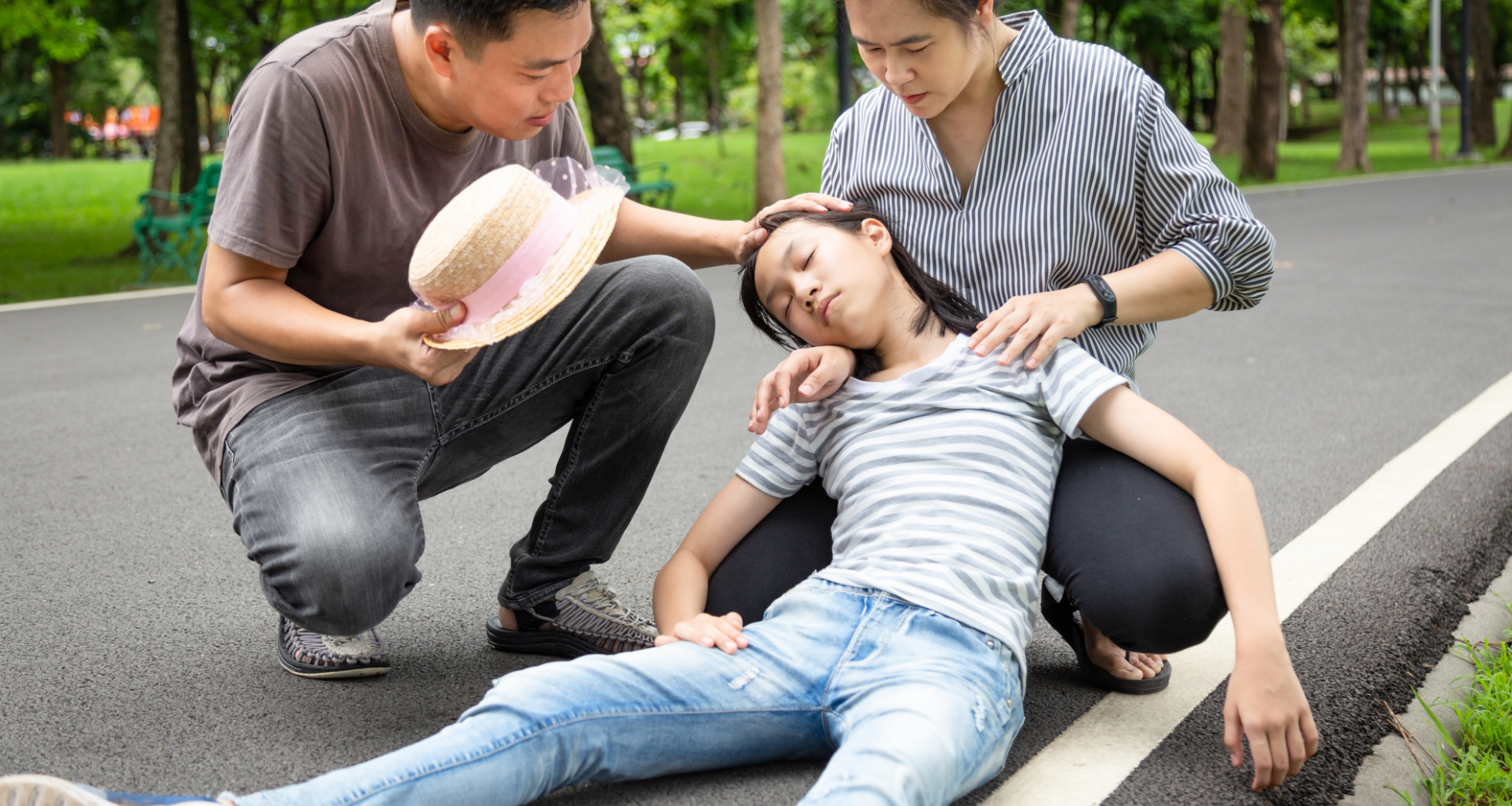 Parents assisting child after fainting episode during fits or syncope in children