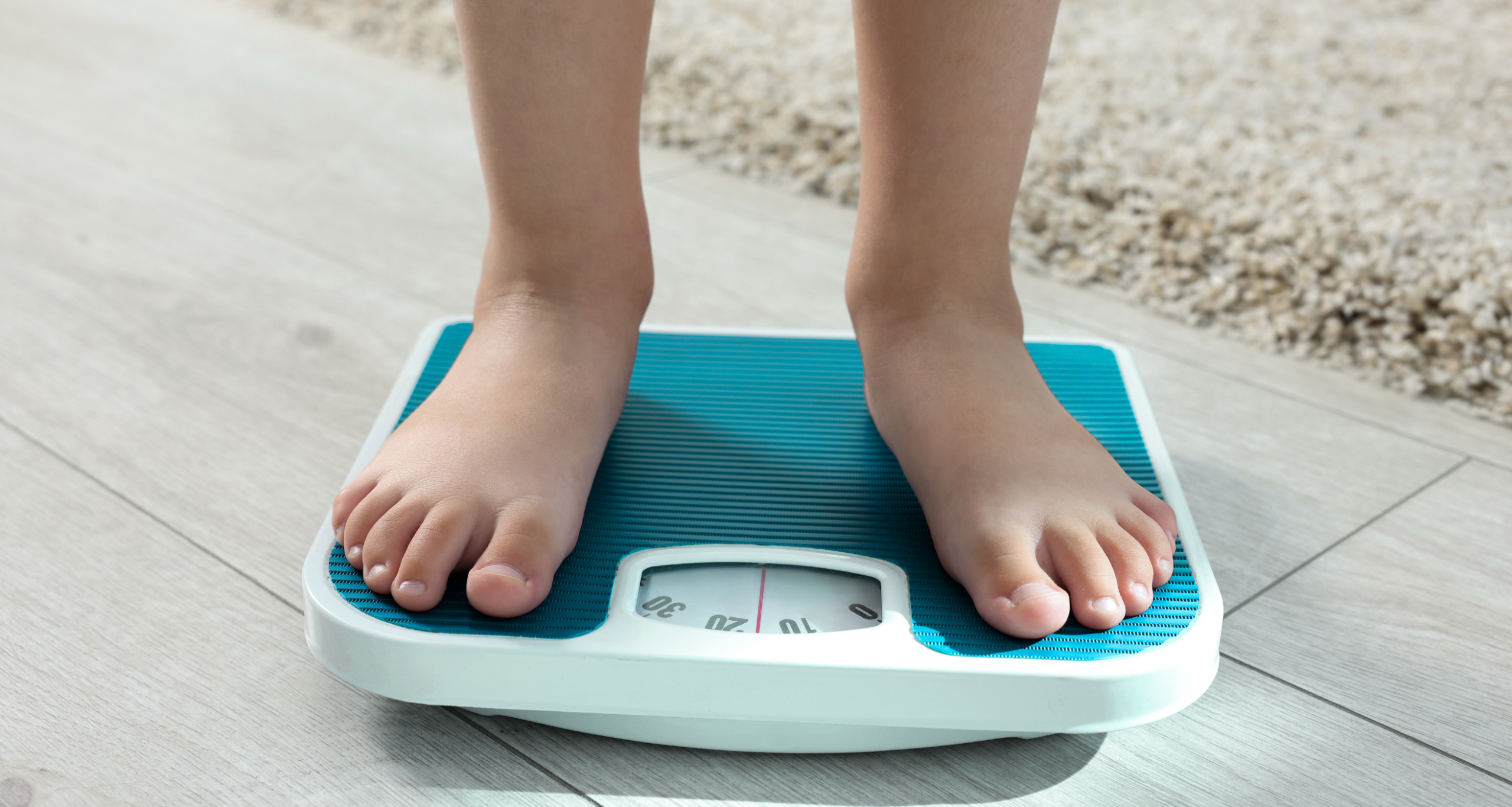 Child standing on weighing scale for monitoring weight problems and pediatric obesity